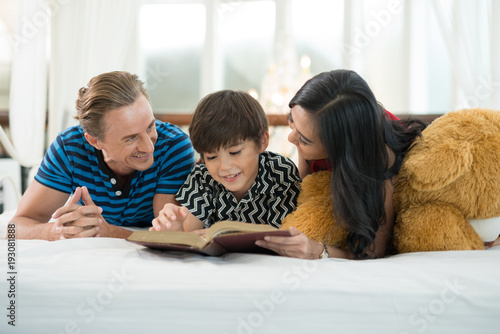 Dad and mom looking at my son reading a book is on the bed in the family education ideas.