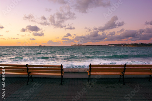 Seafront against sea with surf at sunset