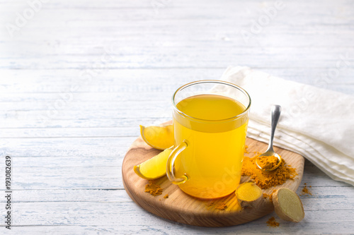 Energy tonic drink with turmeric, ginger, lemon and honey on a wooden board, free space, selective focus
