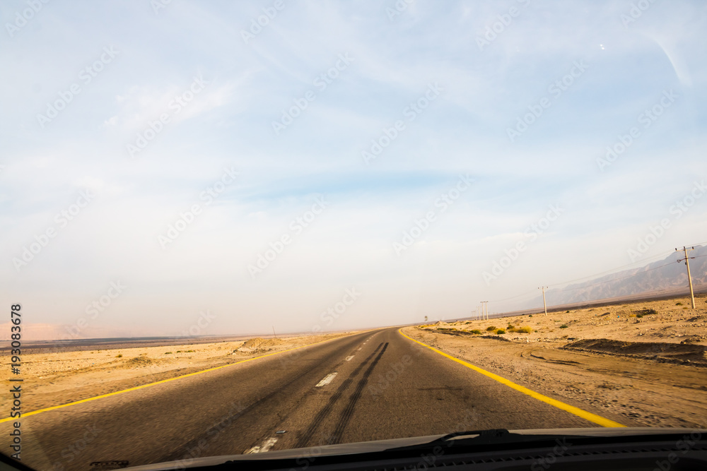 Fototapeta premium Desert highway and mountains through car window not far from Dead sea