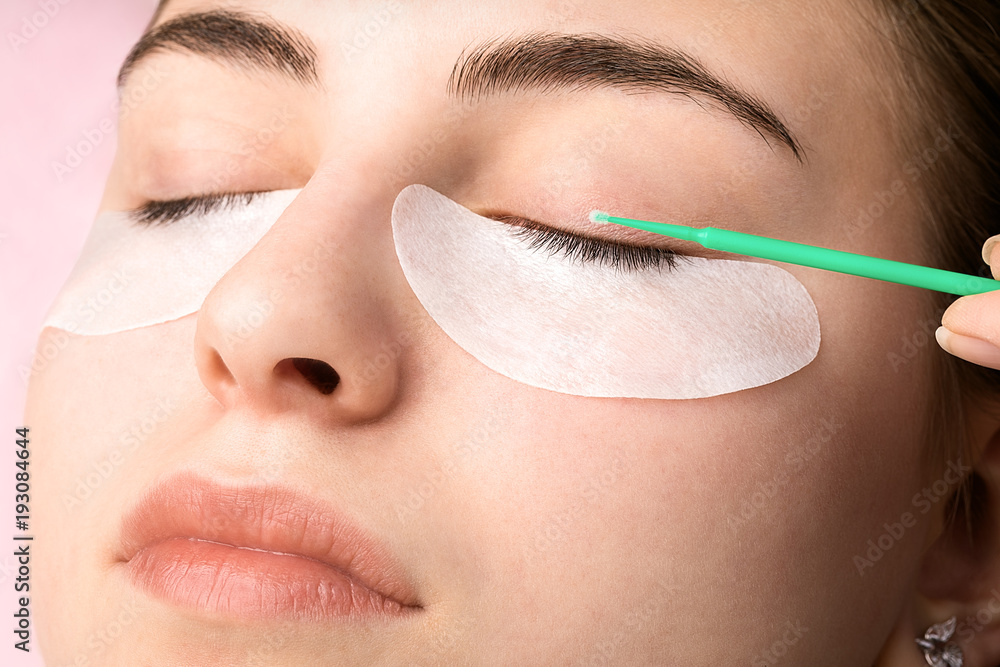 Beautiful young woman with cotton pads around her eyes during eyelash extensions