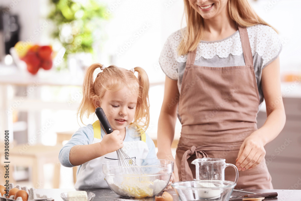 Mother and daughter preparing dough indoors Mother and daughter preparing dough indoors