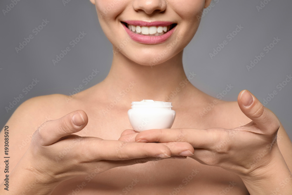 Young woman with jar of cream on grey background, closeup Young woman with jar of cream on grey background, closeup