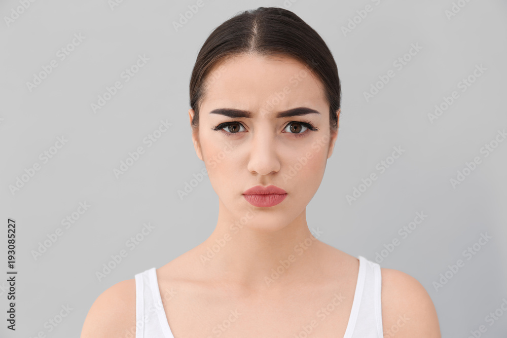 Young woman frowning her eyebrows on light background Young woman frowning her eyebrows on light background