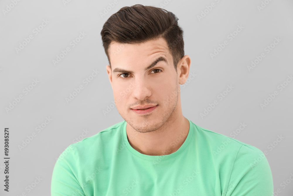 Young man with raised eyebrow on light background Young man with raised eyebrow on light background