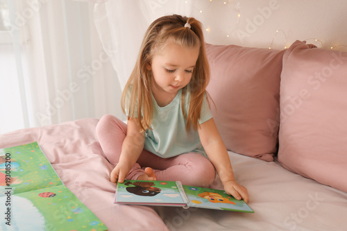Cute little girl reading bo...