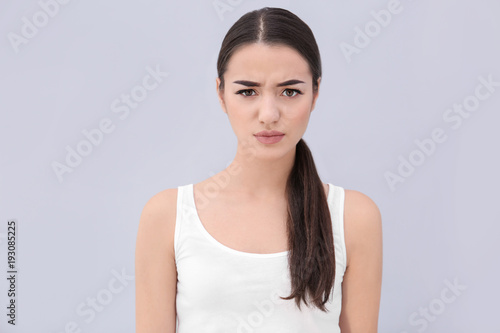 Young woman frowning her eyebrows on light background