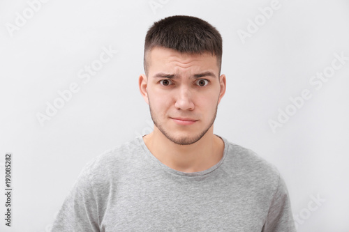 Emotional young man with dyed eyebrows on light background