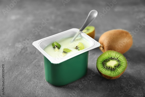 Plastic cup with yummy kiwi yogurt on table