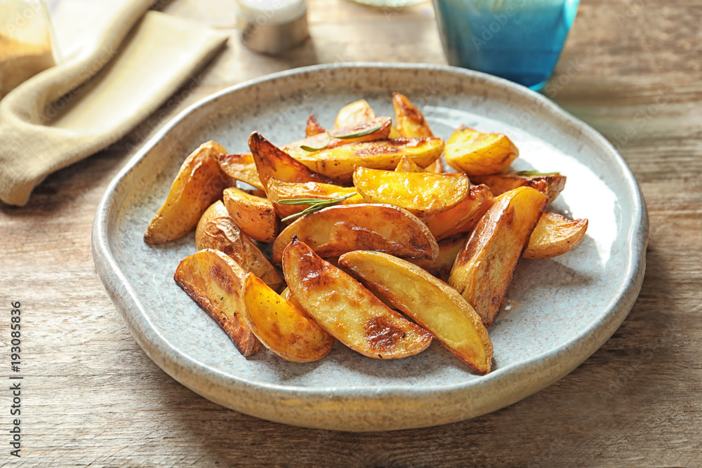 Plate with tasty potato wedges on table Plate with tasty potato wedges on table