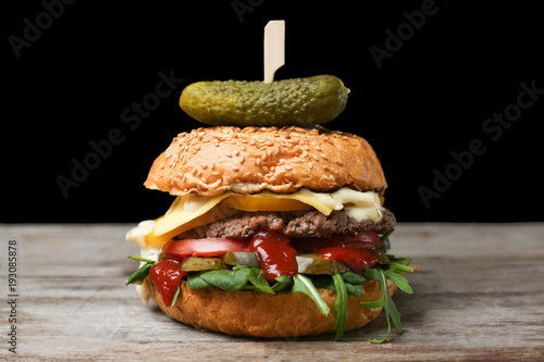 Tasty burger on table against dark background