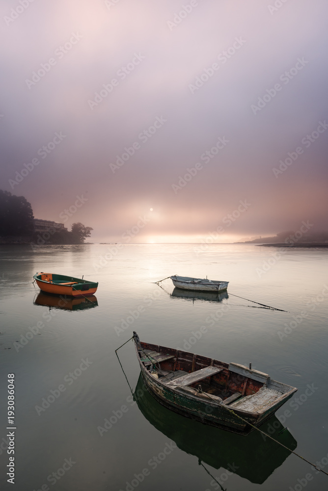 Boats in a foggy sunrise