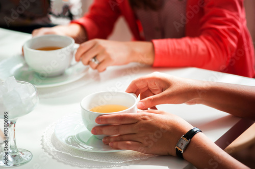 Female hands holding a white cup of tea standing