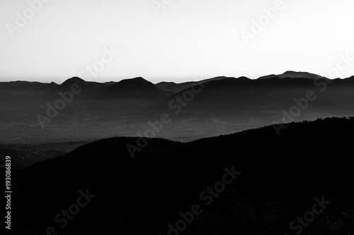 Silhouette of mountain peaks at sunset, under a big , almost empty sky