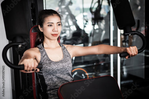 Young Asian woman working out on an exercise machine in the modern gym © Nitiphol