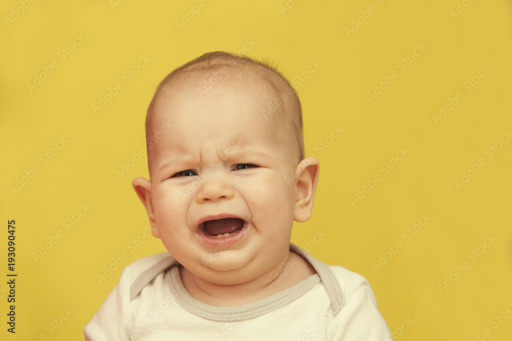 a small child crying on a yellow background