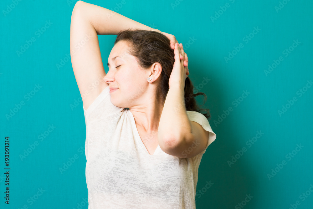 Cheerful girl is stretching her arms after sleeping. She closed her eyes happily and smiling.