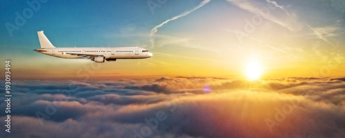 Airplane jetliner flying above clouds in beautiful sunset light.