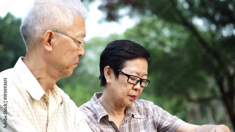 Asian senior couple using tablet together in park Asian senior couple using tablet together in park
