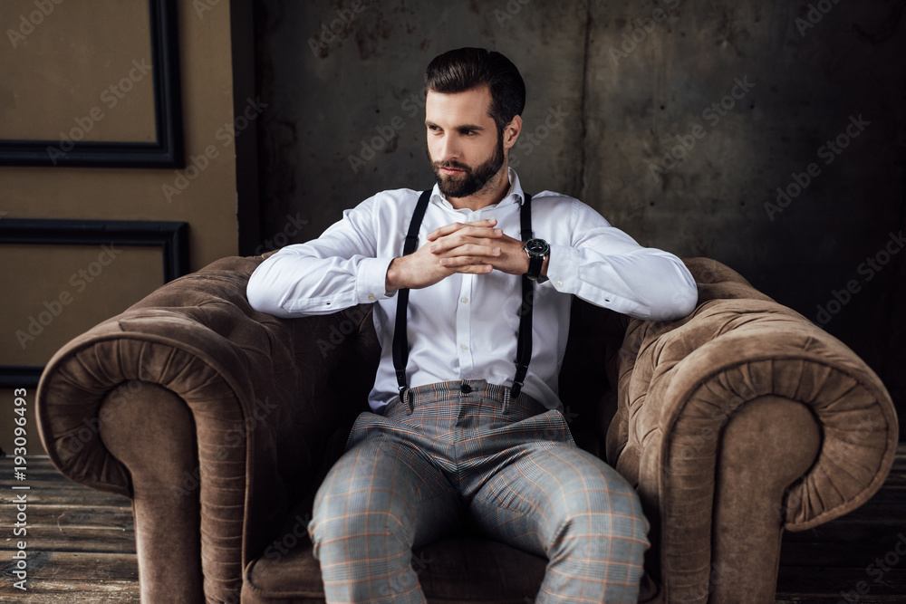 handsome fashionable man thinking and sitting in armchair handsome fashionable man thinking and sitting in armchair