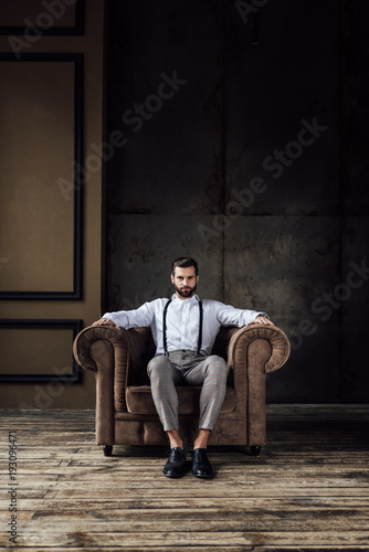 handsome stylish man thinking and sitting in armchair