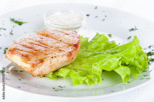 Turkey steak with lettuce and sauce on a white background