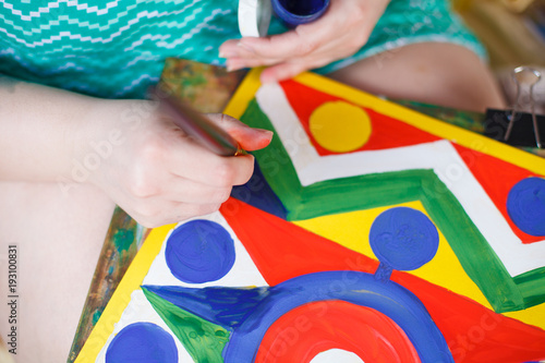 Художник женщина за работой, рисует картину из геометрических узоров разноцветными красками