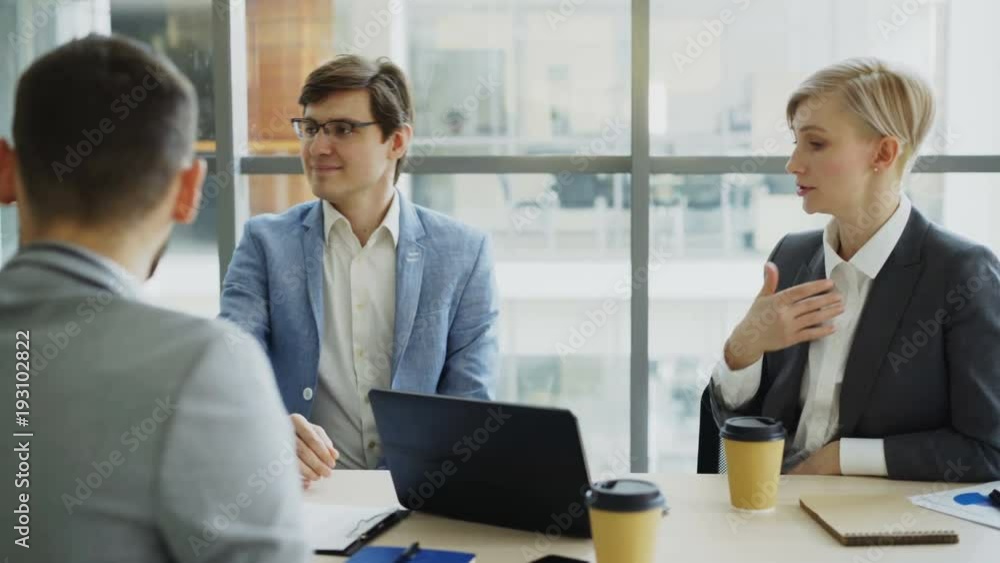 Business team chatting while sitting in modern office indoors during coffee break Business team chatting while sitting in modern office indoors during coffee break