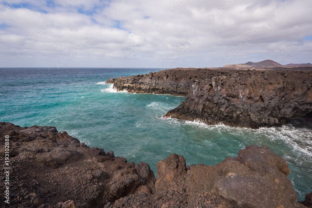 Lanzarote landscape. Los Hervideros coastline, lava caves, cliffs and wavy ocean. No people appears in the scene. Lanzarote landscape. Los Hervideros coastline, lava caves, cliffs and wavy ocean. No people appears in the scene.
