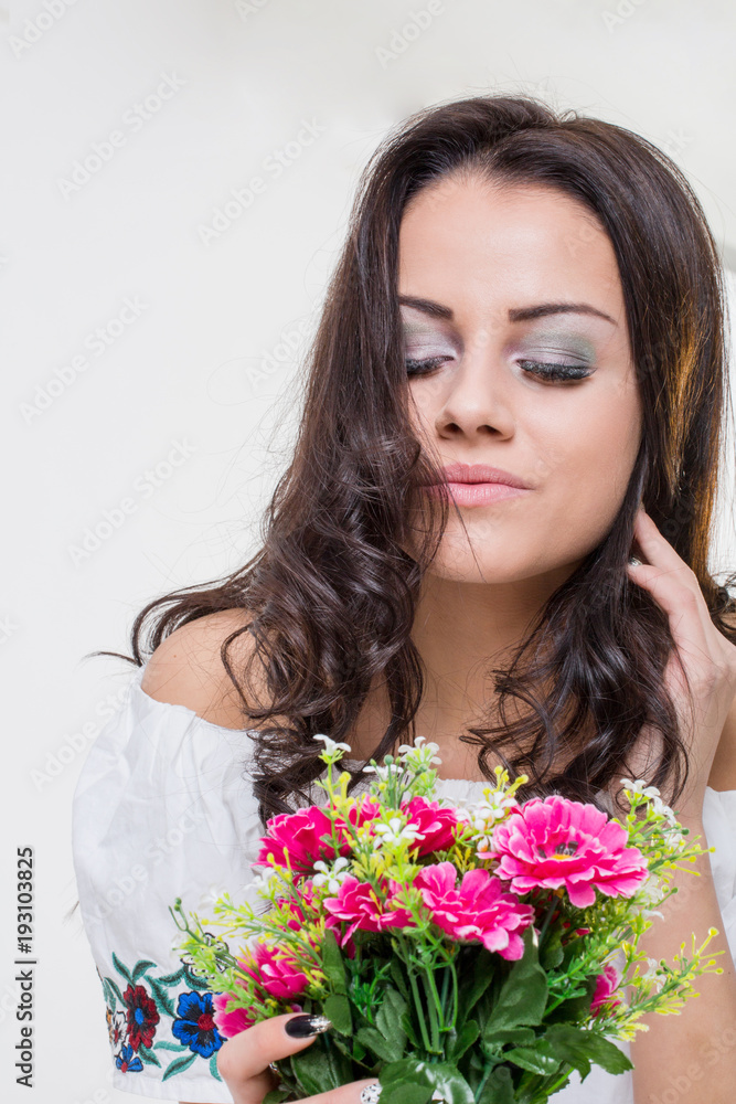 Attractive young brunette woman holding fresh flowers Attractive young brunette woman holding fresh flowers