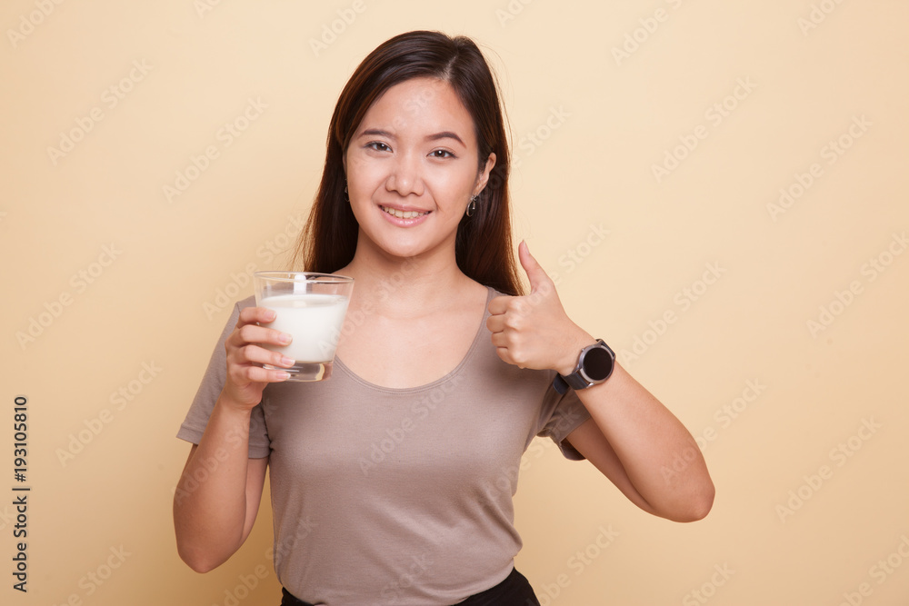 Healthy Asian woman drinking a glass of milk thumbs up. Healthy Asian woman drinking a glass of milk thumbs up.
