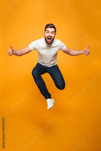 Fototapet Full length portrait of an excited bearded man jumping