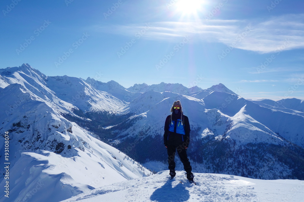 Top of Kopa Kondracka with a young man during winter with a view on Kasprowy Wierch, Zakopane, Tatry mountains, Poland