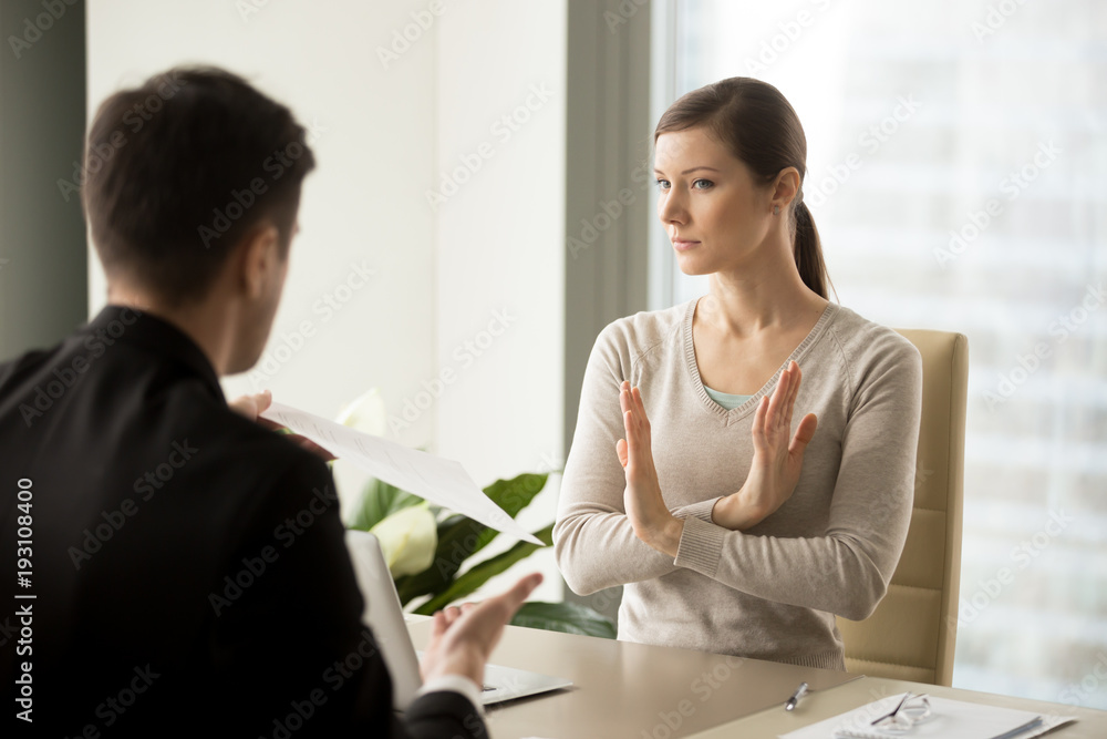 Unconvinced in honesty of business agreement female entrepreneur refusing to sign contact with businessman. Skeptical young woman rejecting job offer when sitting at desk in front of hiring manager Unconvinced in honesty of business agreement female entrepreneur refusing to sign contact with businessman. Skeptical young woman rejecting job offer when sitting at desk in front of hiring manager