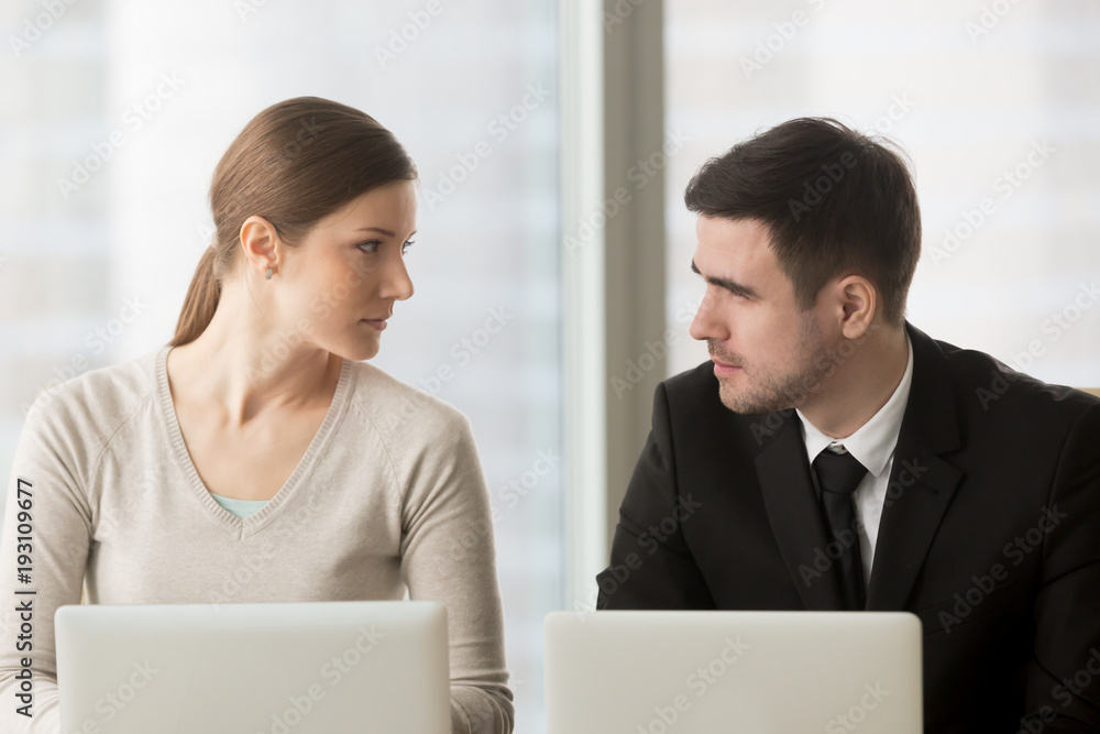 Female and male colleagues carefully looking on each other when sitting at desk. Competition in work, professional rivalry and jealousy. Feminism, equal gender rights and opportunities in business Female and male colleagues carefully looking on each other when sitting at desk. Competition in work, professional rivalry and jealousy. Feminism, equal gender rights and opportunities in business