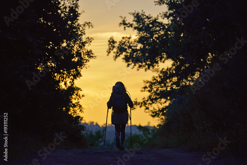 young girl walking at surnrise along the Way of St. James few kilometers from Santiago, Santiago de Compostela, Galicia, Spain photo