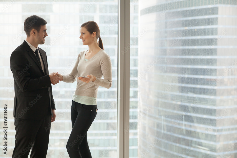Smiling female secretary welcoming male client in company office. Confident businesswoman introducing herself to business partner, congratulating colleague with promising deal. Productive negotiation Smiling female secretary welcoming male client in company office. Confident businesswoman introducing herself to business partner, congratulating colleague with promising deal. Productive negotiation