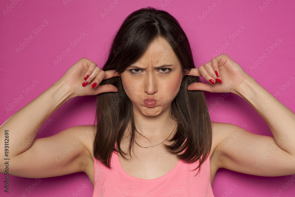 Young funny woman making silly faces on pink background Young funny woman making silly faces on pink background