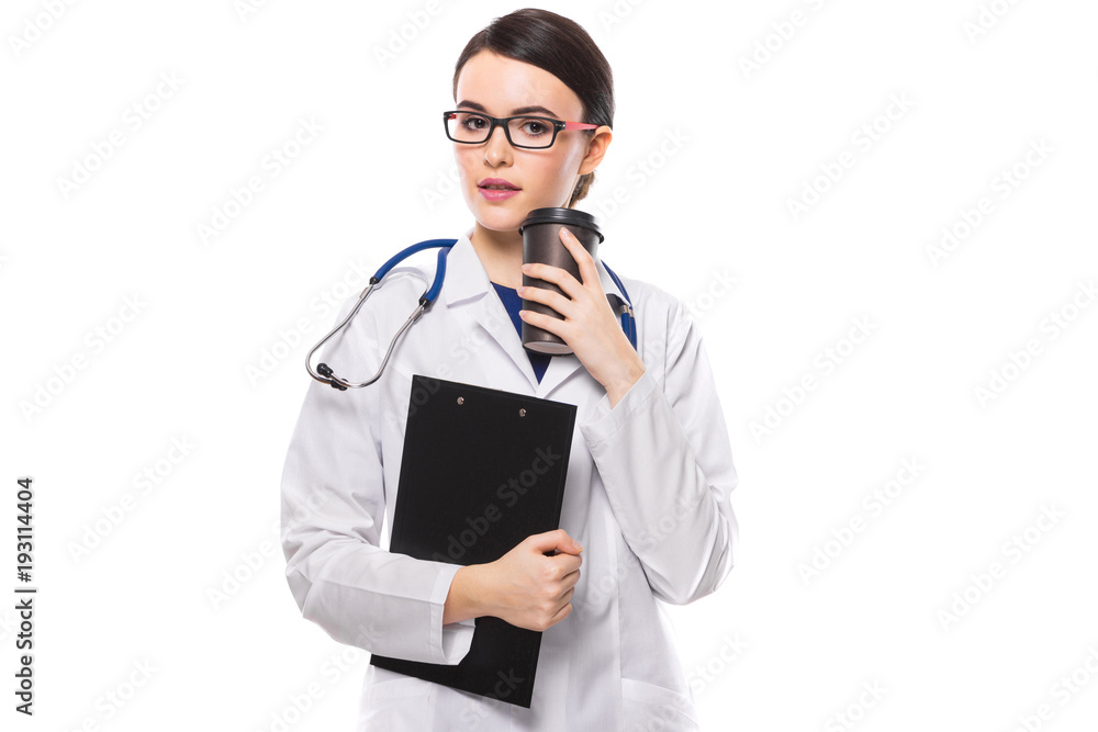 Young woman doctor with stethoscope holding clipboard and cup of coffee in her hands in white uniform on white background Young woman doctor with stethoscope holding clipboard and cup of coffee in her hands in white uniform on white background