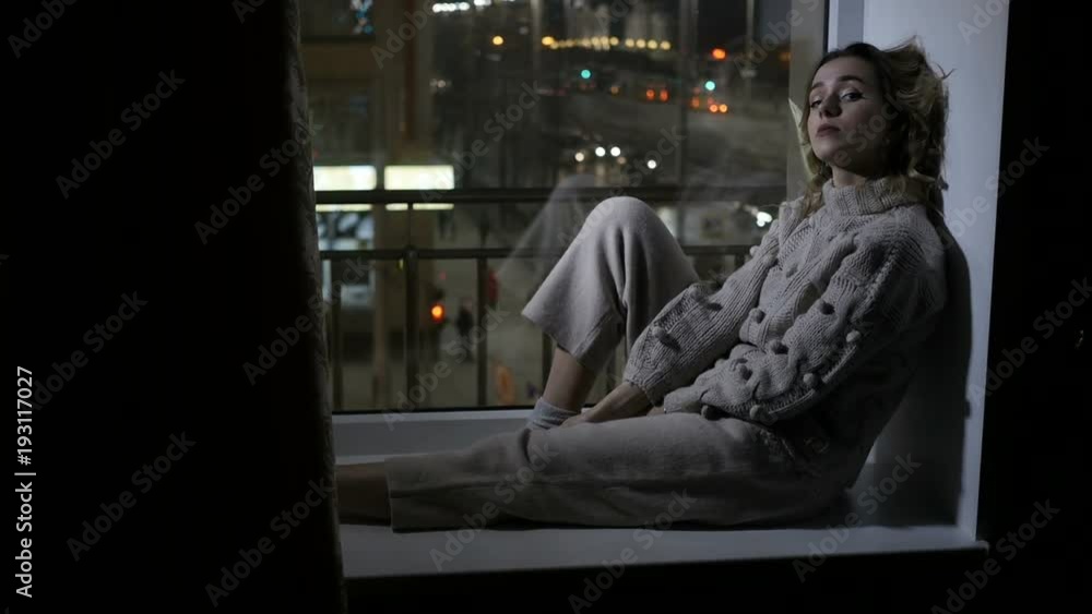 Woman is sitting on window sill Woman is sitting on window sill