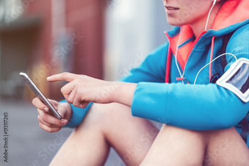Woman adjusting running application with mobile phone before city workout