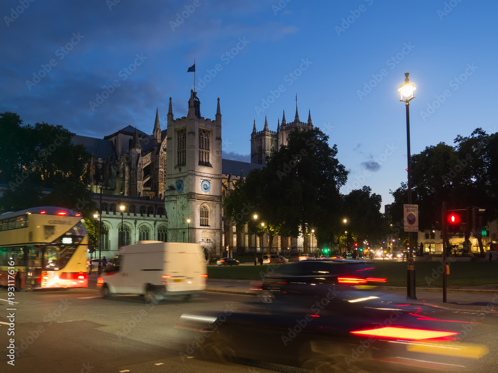 Fototapeta premium View of the Church of St Margaret with the Westminster Abbey in the background on Parliament Square, London all illuminated at dusk.