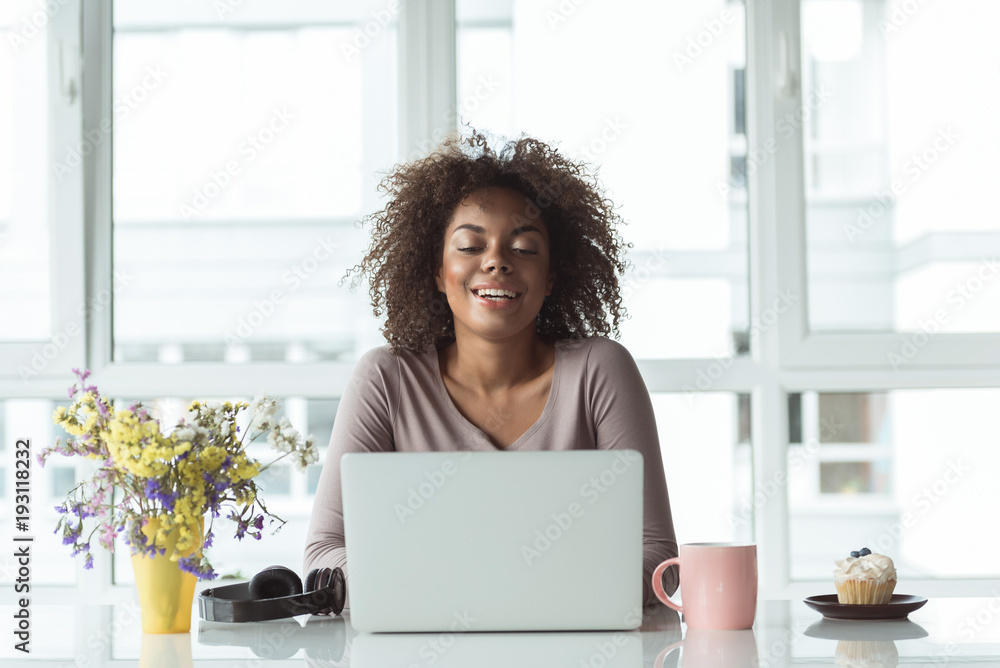 Portrait of outgoing young female typing on laptop while sitting at desk in office Portrait of outgoing young female typing on laptop while sitting at desk in office