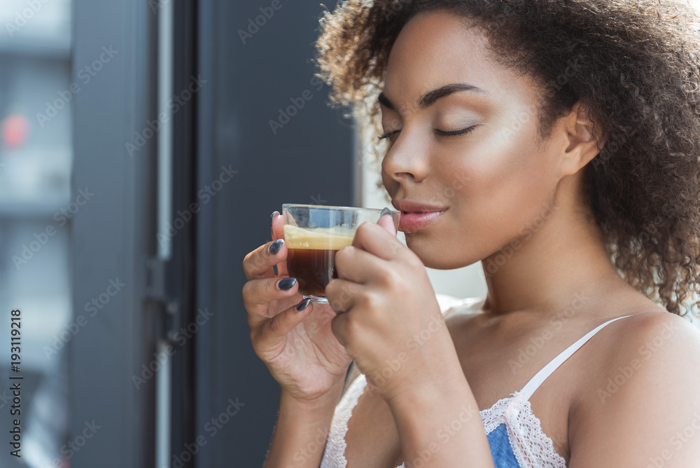 African woman expressing satisfaction while tasting hot beverage in morning African woman expressing satisfaction while tasting hot beverage in morning
