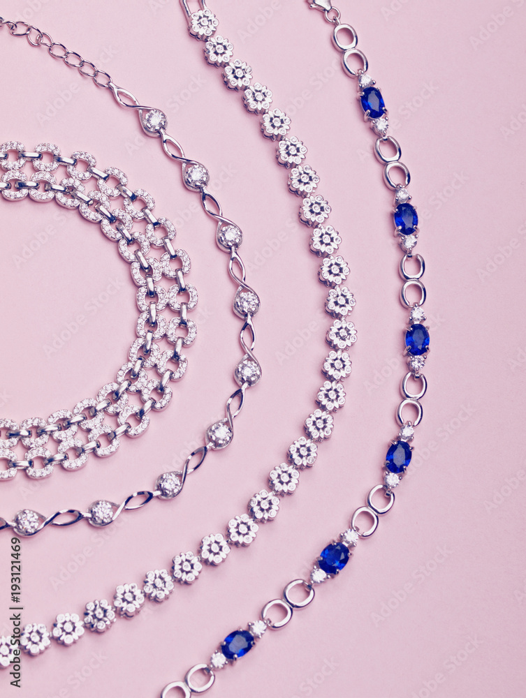 Obraz premium Set ot silver stylish necklaces isolated on light pink background. Jewelry pieces. Flat lay