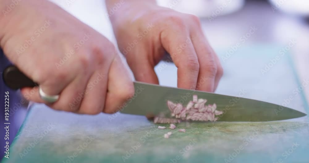 4K Close up on the hands of a skilled chef cutting a shallot on chopping board 4K Close up on the hands of a skilled chef cutting a shallot on chopping board