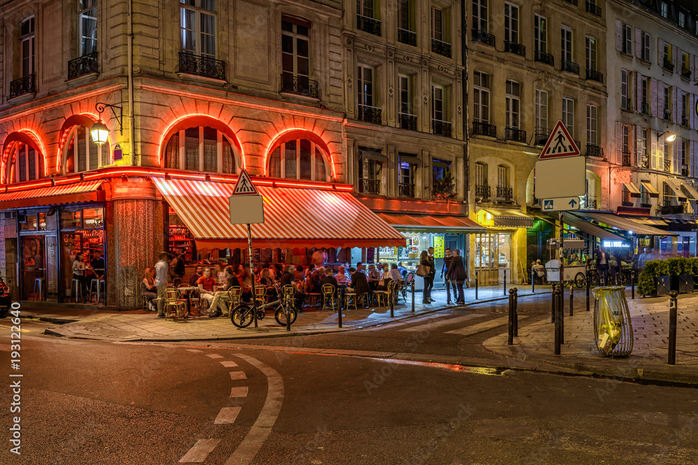 Naklejka premium Przytulna ulica ze stołami kawiarni w Paryżu w nocy, Francja
