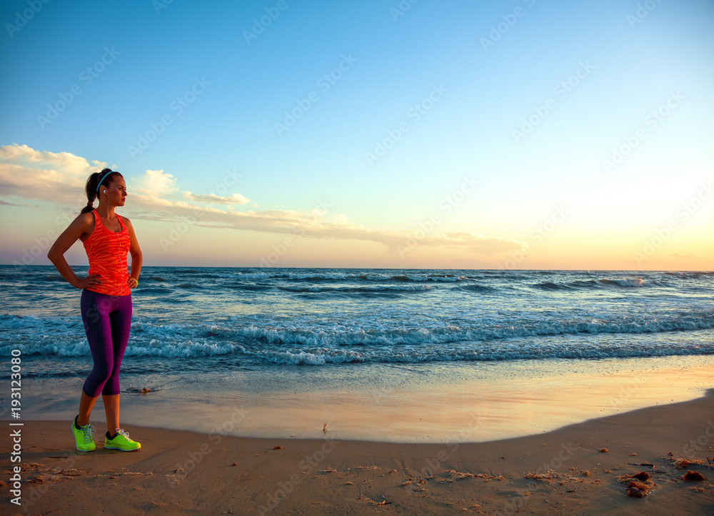 young woman on seashore at sunset looking into distance