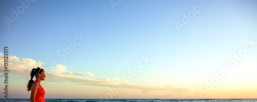 active woman in sports gear on seashore at sunset walking