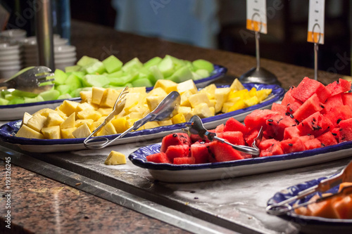 Sliced watermelons and pineapples on the plates; 